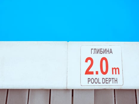 The edge of the swimming pool with the table with information of the depth in English and Ukrainian language. Sport, safety, recreation and relax concept. photo