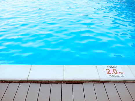 The edge of the swimming pool with the table with information of the depth in English and Ukrainian language. Sport, safety, recreation and relax concept. photo