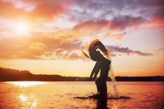 Young, beautiful girl walking at the beach at sunset. Stylish woman with long hair standing in blouse and jeans shorts photo