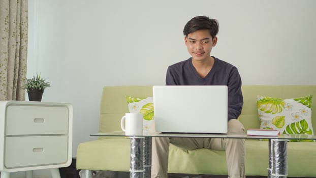 asian man doing something on laptop at home happily photo