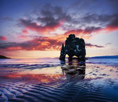 Is a spectacular rock in the sea on the Northern coast of Iceland. Legends say it is a petrified troll. On this photo Hvitserkur reflects in the sea water after the midnight sunset