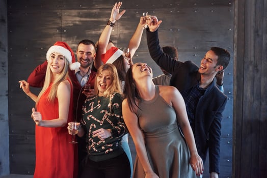 Party with friends. They love Christmas. Group of cheerful young people carrying sparklers and champagne flutes dancing in new year party and looking happy. Concepts about togetherness lifestyle photo