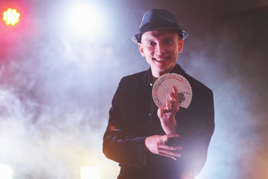 Magician showing trick with playing cards. Magic or dexterity, circus, gambling. Prestidigitator in dark room with fog photo