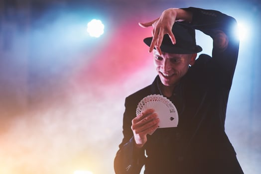 Magician showing trick with playing cards. Magic or dexterity, circus, gambling. Prestidigitator in dark room with fog photo
