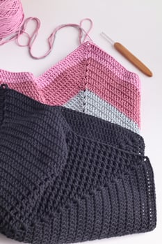Crochet granny square bag. Crochet market bag with wood crochet needle and yarn balls on white background. Handmade and craft. photo