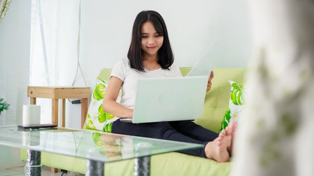 Young beautiful Asian woman working from home using laptop photo