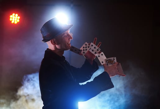 Magician showing trick with playing cards. Magic or dexterity, circus, gambling. Prestidigitator in dark room with fog photo