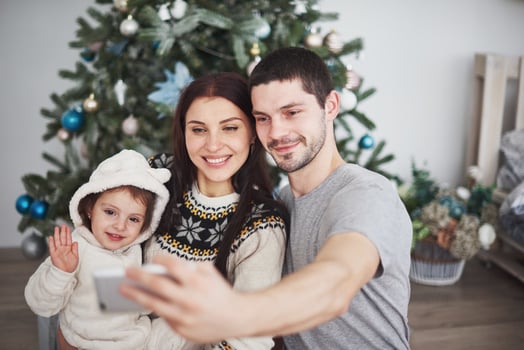 Family gathered around a Christmas tree, using a tablet photo