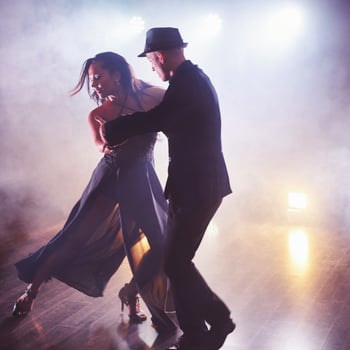 Skillful dancers performing in the dark room under the concert light and smoke. Sensual couple performing an artistic and emotional contemporary dance photo