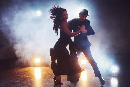 Skillful dancers performing in the dark room under the concert light and smoke. Sensual couple performing an artistic and emotional contemporary dance photo