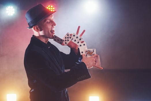 Magician showing trick with playing cards. Magic or dexterity, circus, gambling. Prestidigitator in dark room with fog photo