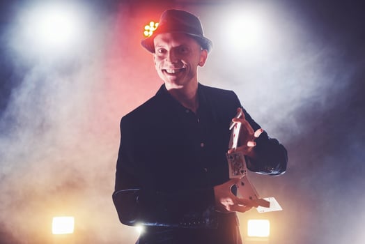 Magician showing trick with playing cards. Magic or dexterity, circus, gambling. Prestidigitator in dark room with fog photo