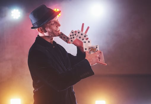 Magician showing trick with playing cards. Magic or dexterity, circus, gambling. Prestidigitator in dark room with fog photo