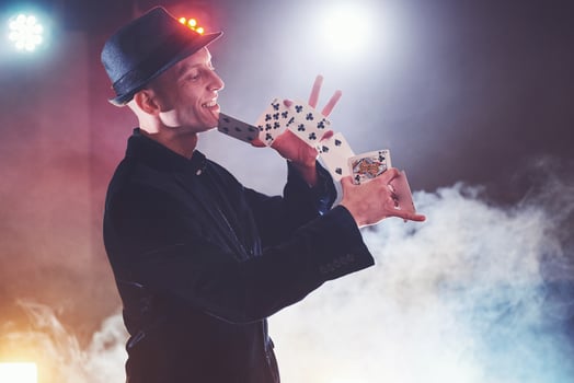 Magician showing trick with playing cards. Magic or dexterity, circus, gambling. Prestidigitator in dark room with fog photo