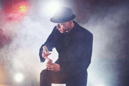 Magician showing trick with playing cards. Magic or dexterity, circus, gambling. Prestidigitator in dark room with fog photo