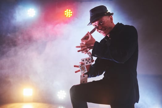Magician showing trick with playing cards. Magic or dexterity, circus, gambling. Prestidigitator in dark room with fog photo