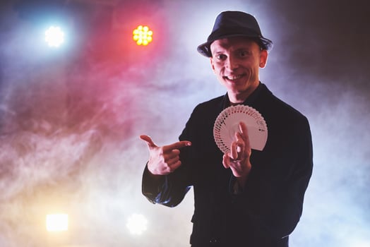 Magician showing trick with playing cards. Magic or dexterity, circus, gambling. Prestidigitator in dark room with fog photo