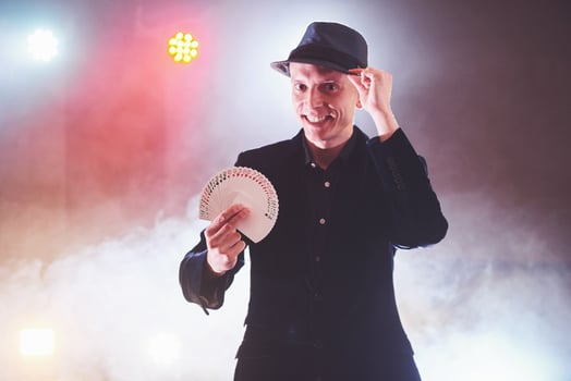 Magician showing trick with playing cards. Magic or dexterity, circus, gambling. Prestidigitator in dark room with fog photo