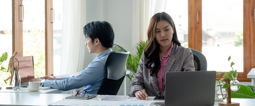 Portrait of young asian woman sitting at her desk with laptop while looking at laptop  in modern office. photo