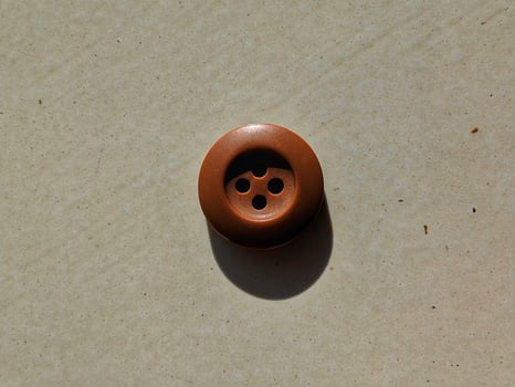 Button up shirt with three brown thread holes. photo