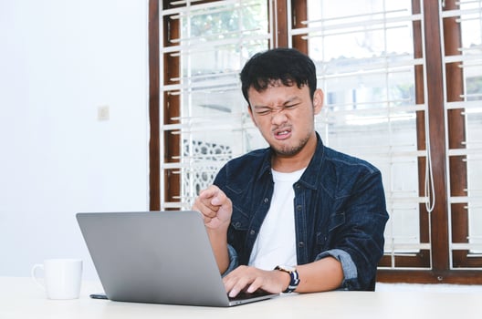 Young Asian man angry and mad what he see in the laptop when work photo