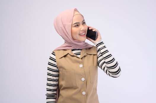 Portrait of beautiful woman with hijab using cellphone on white background photo