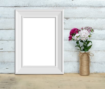 Vertical A4 Vintage White Wooden Frame mockup near a bouquet of sweet-william  stands on a wooden table on a painted white wooden background. Rustic style, simple beauty. 3d render. photo