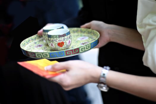 Close up of the hands of bride and groom holding a tea set during a Chinese wedding tea ceremony photo