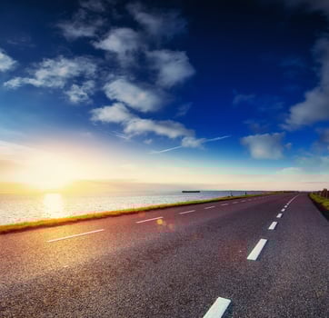 Asphalt road along the sea at sunset photo
