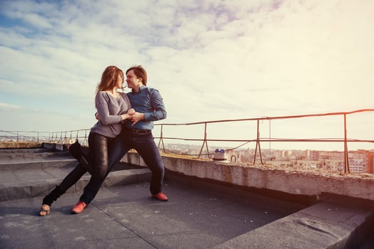 young couple dancing on the roof of a tall building photo