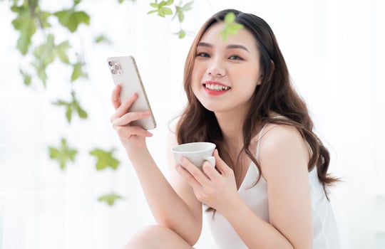 Young Asian woman using smartphone at home in the morning photo