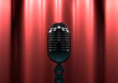 Vintage microphone on stage with red curtains. Moody stage lighting creates drama and suspense. photo