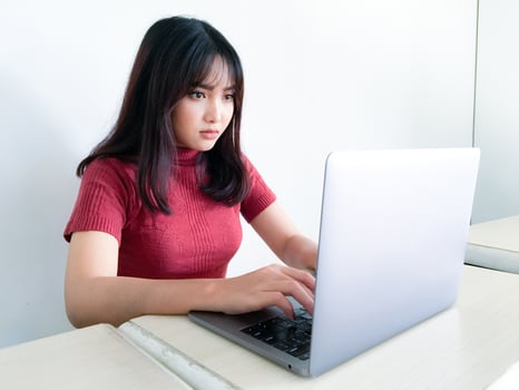 Asian beautiful girl serious or thinking in the front of laptop on the isolated white background photo