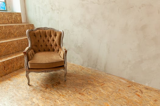 Beautiful luxury classic biege clean interior room in grunge style with brown baroque armchair. Vintage antique brown-gray chair standing beside wall. Minimalist home design. photo