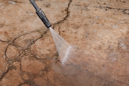 Worker cleaning dirty floor with high pressure washer photo