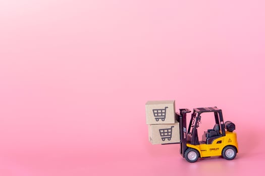 Logistics, and delivery service - Forklift model and paper cartons or parcel with a shopping cart logo on Pink background. Shopping service on The online web and offers home delivery. photo