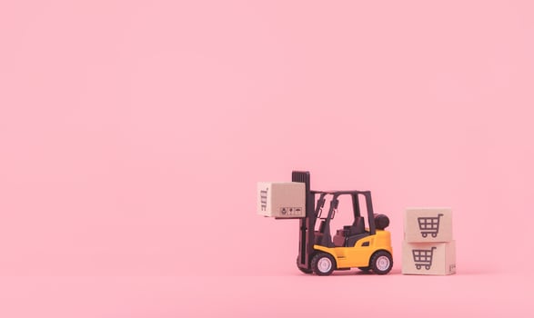 Logistics, and delivery service - Forklift model and paper cartons or parcel with a shopping cart logo on Pink background. Shopping service on The online web and offers home delivery. photo