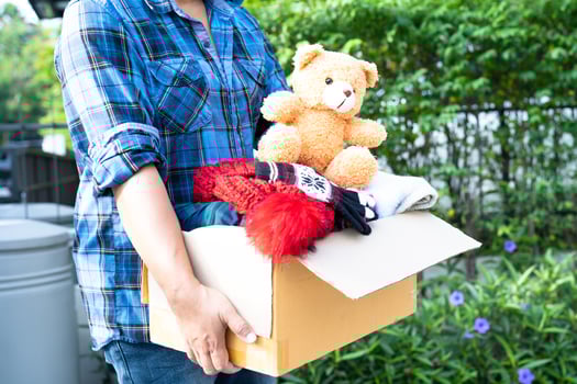 Holding clothing donation box with used clothes and doll at home to support help for poor people in the world. photo