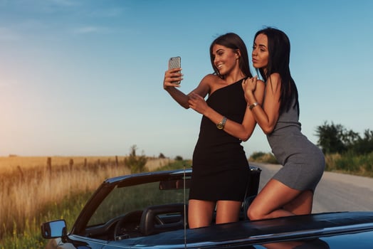 Two sexy brunette woman standing near cabriolet on the road photo