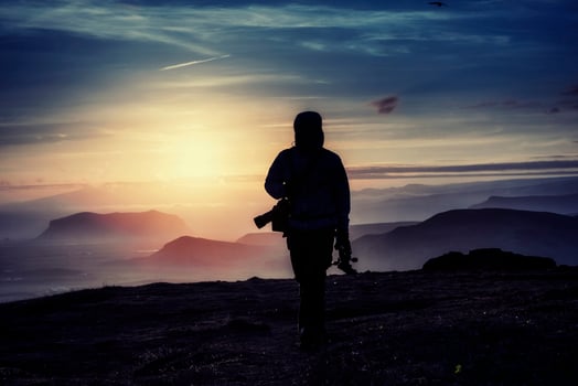 Happy man standing on a cliff at sunset photo