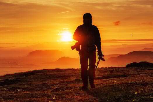 Happy man standing on a cliff at sunset photo