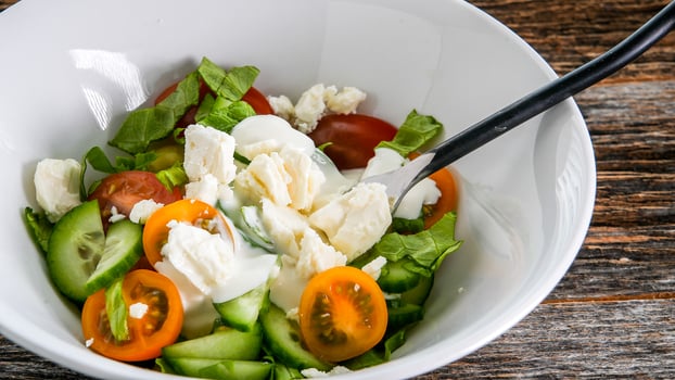 Vegetables salad with dressing inside white bowl on rustic table photo