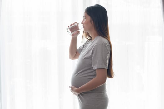 Young pregnant woman drinking water at home, healthcare and pregnancy care concept photo