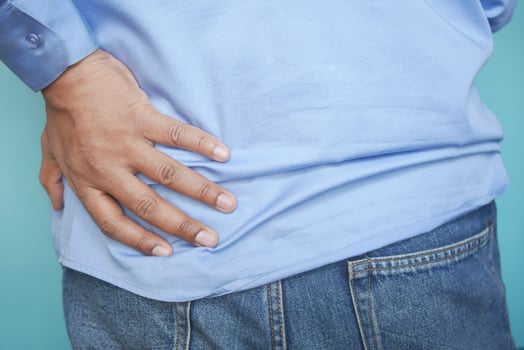 young man suffering back pain close up photo