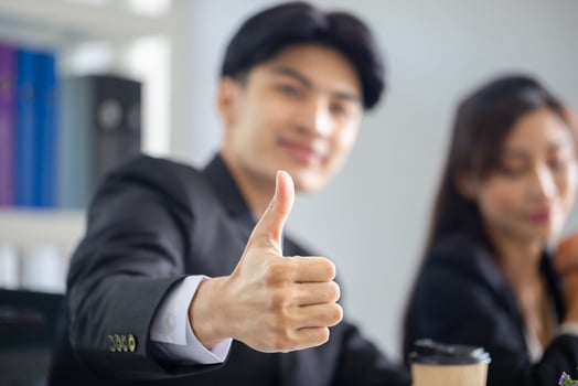 Cheerful business man showing thumbs up with group of businesspeople meeting in office photo