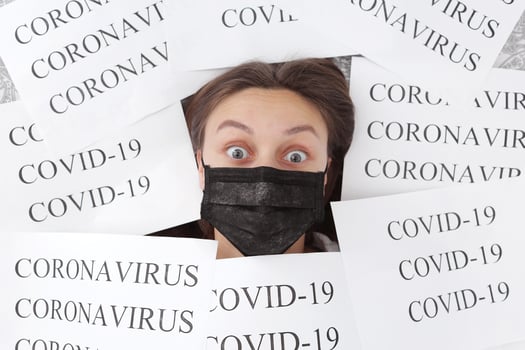 shocked young beautiful woman in medical black mask lies in papers with inscription coronavirus and covid-19. Quarantine at home. selective focus photo
