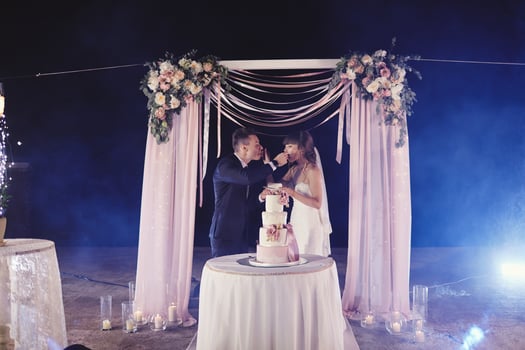 gorgeous bride and stylish groom tasting their stylish wedding cake. happy newlywed couple eating piece of cake, funny emotional moment photo