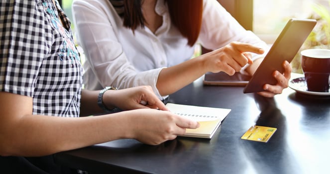Two Asian women drinking coffee in a cafe and shopping online on smart phones photo