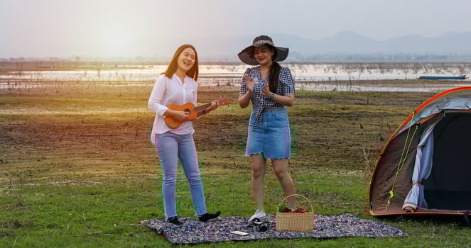 A group of Asian friends playing Ukelele and spending time making a picnic in the summer holidays.They are happy and have fun on holidays. photo
