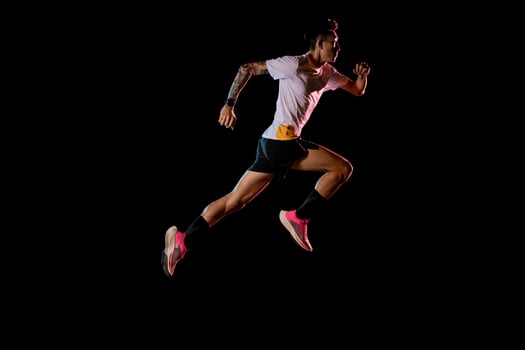 Asian man young sprinter runner running in studio on black background photo